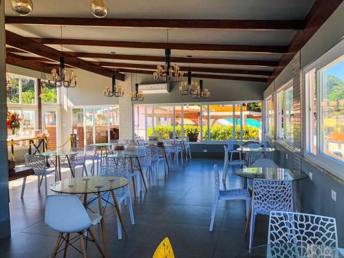 a dining room with tables and chairs and windows at Cristal Pousada in Morro de São Paulo