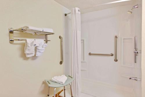 a white bathroom with a shower and a stool at Days Inn by Wyndham Charlotte/Woodlawn Near Carowinds in Charlotte