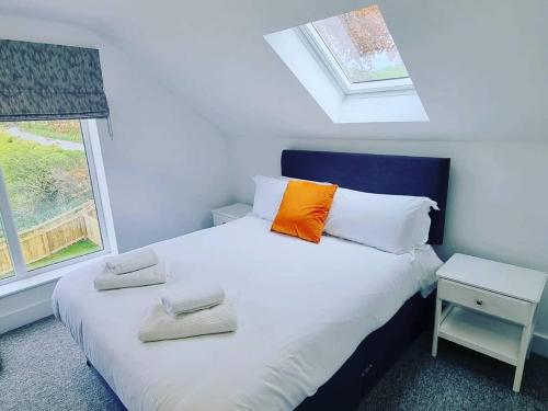 a bedroom with a white bed with an orange pillow at Beech Cottage in Rothbury