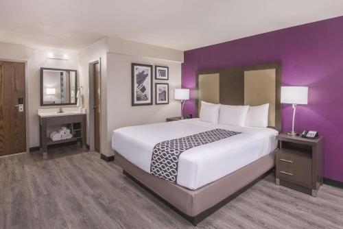 ein Hotelzimmer mit einem großen Bett und lila Wänden in der Unterkunft La Quinta by Wyndham Festus - St. Louis South in Festus