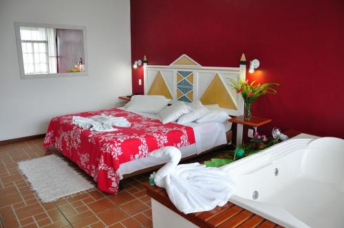 a bedroom with a large bed and a bath tub at Pousada e Spa Vrindávana in Teresópolis