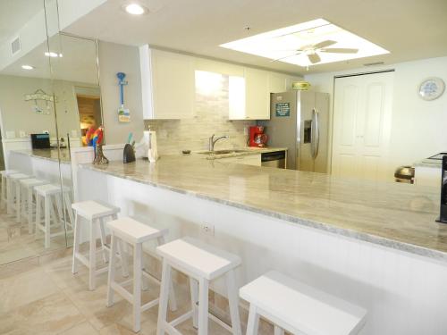 a kitchen with a counter with white stools at Vacation in Comfort and luxury - "THE SHERWIN" Oceanfront Condominium 906 in Daytona Beach Shores