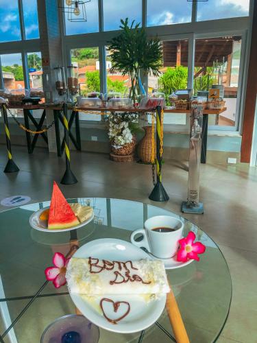 a table with two plates of food and a cup of coffee at Cristal Pousada in Morro de São Paulo