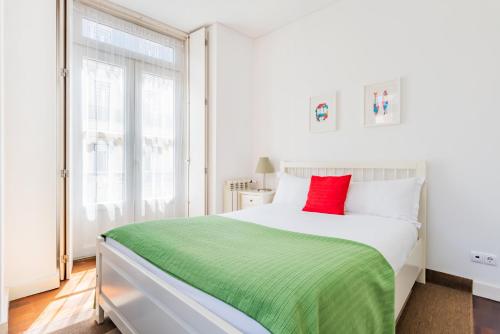 a white bedroom with a red pillow on a bed at Chiado Prime Camões Apartment in Lisbon