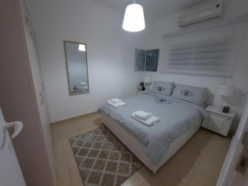 een witte slaapkamer met een bed en een spiegel bij Akhva Accommodation Unit-אחווה יחידת אירוח in Arad