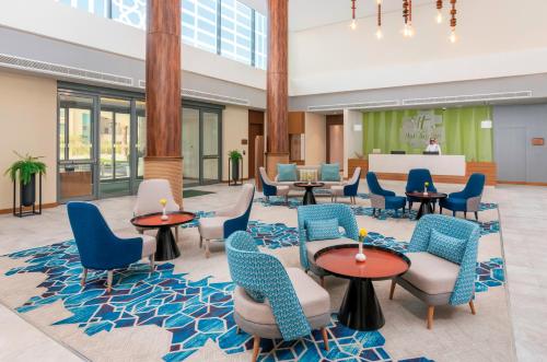 a lobby with blue chairs and tables in a building at Holiday Inn & Suites Al Jubail, an IHG Hotel in Al Jubail