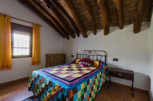 1 dormitorio con 1 cama con colcha colorida en Cortijo Cabrilla, en Periana