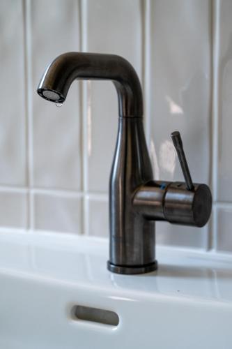 a black faucet on a white sink at MAAJO Boutique Hotel in Valgalciems