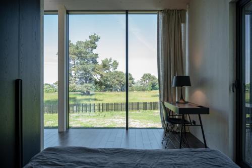 a bedroom with a bed and a desk and a large window at MAAJO Boutique Hotel in Valgalciems