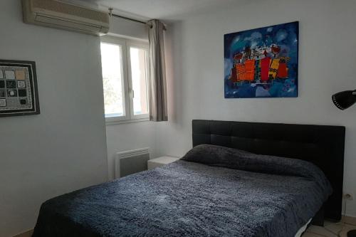 une chambre avec un lit et un tableau au mur dans l'établissement T2 avec une agréable vue jardin Emeraude 35, à Canet