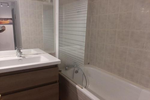 une salle de bain avec un lavabo, une douche et une baignoire dans l'établissement T2 avec une agréable vue jardin Emeraude 35, à Canet