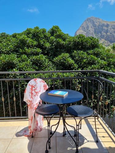 a table and chairs on a balcony with a view of the mountains at Blue Lovely House in San Vito lo Capo
