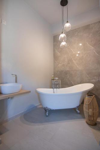 a bathroom with a large white tub and a sink at Georgianna's suite with private pool , 'greysuite' in Kómpoi