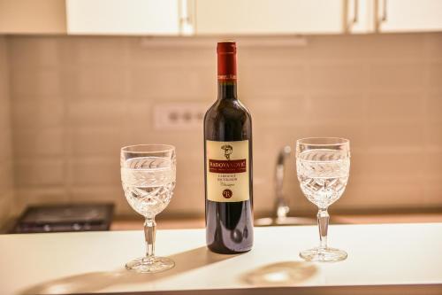 a bottle of wine and two glasses on a counter at Apartman Savić in Bajina Bašta