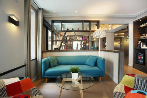 a living room with a blue couch and a glass table at Hotel Eiffel Capitol in Paris