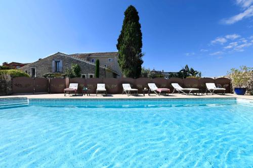 a swimming pool with a bunch of chairs around it at Gîte des Demoiselles en Luberon in Roussillon