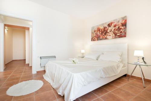 biała sypialnia z białym łóżkiem i obrazem na ścianie w obiekcie Guilford old town Apartment w Korfu