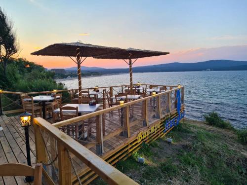 a restaurant with tables and an umbrella on the water at Hotel Nikola in Primorsko