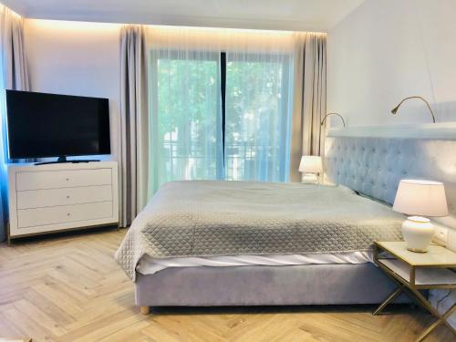 a bedroom with a large bed and a flat screen tv at Luxury Apartments in Residence Maritime in Międzyzdroje
