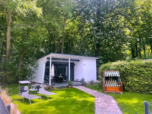a small white shed in a garden with chairs and tables at Bungalowpark am Salzhaff in Klein Strömkendorf
