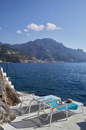 a group of chairs and a table on the water at Palazzo Avino in Ravello