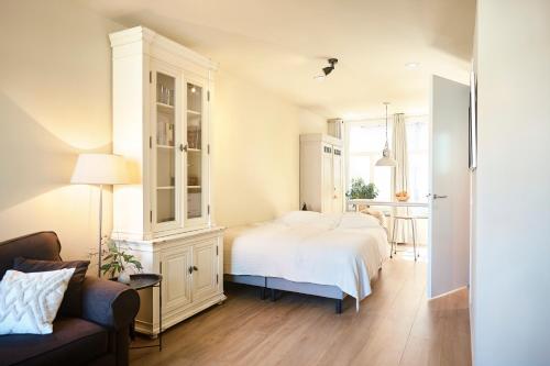 a bedroom with a white bed and a couch at Studio Compact in Middelburg