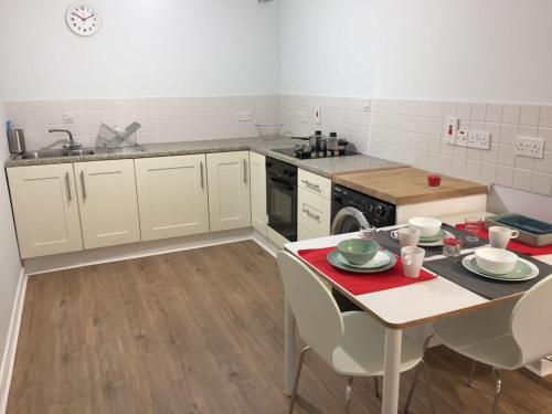 uma cozinha com armários brancos, uma mesa e um lavatório em Hugh O'Neill Ambassador Suite em Dungannon