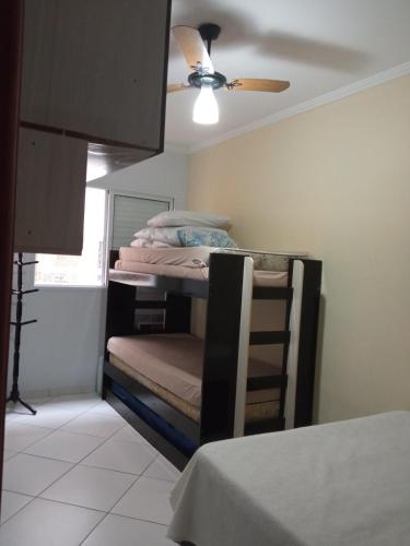 a bedroom with a bunk bed with a ceiling fan at Praia Grande canto do forte in Praia Grande