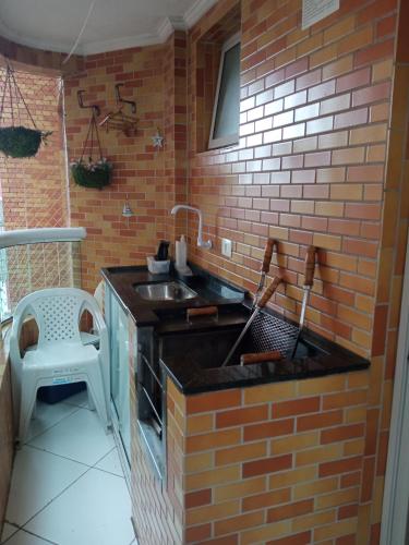 a kitchen with a sink and a brick wall at Praia Grande canto do forte in Praia Grande