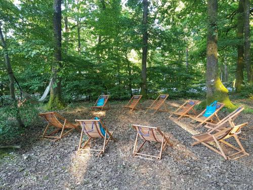 un groupe de chaises et de tables dans les bois dans l'établissement Camping de la Forêt Seasonova, à Sillé-le-Guillaume