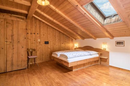 1 dormitorio con 1 cama en una habitación con paredes de madera en Ferienwohnung Stockrose Nusserhof, en Avelengo