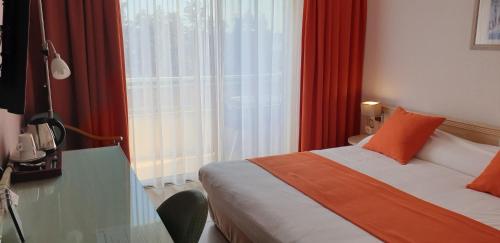 a bedroom with a bed and a window with red curtains at Logis Hôtel & Restaurant Le Fleurance in Fleurance