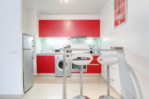 - une cuisine avec des placards rouges et un lave-linge dans l'établissement IMMOGROOM - 8 min from the Palais - AC - Quai St Pierre, à Cannes