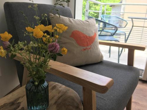 a vase of flowers sitting on a table next to a chair at Hôtel Le Cassini in Le Freney-dʼOisans