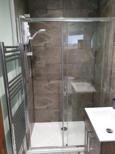 a shower with a glass door in a bathroom at Lavenderescape. in Seahouses