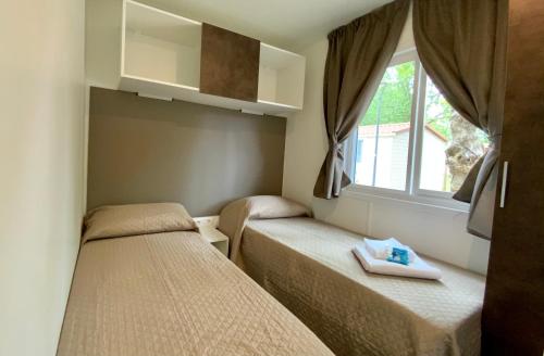 Habitación pequeña con 2 camas y ventana en Volare Camp in Villaggio San Francesco, en Duna Verde