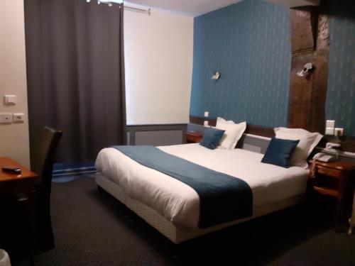 ein Schlafzimmer mit einem großen Bett mit blauer Wand in der Unterkunft Logis Hôtel Restaurant de l'Ecu in Montbard