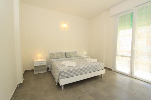 a white bedroom with a bed and a window at Apartment Pineta 11 in Lido di Pomposa