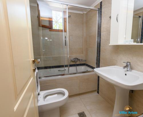 a bathroom with a sink and a toilet and a tub at Villa Arion in Nydri