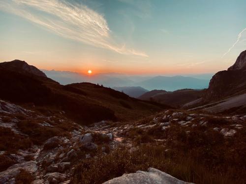 a sunset over a mountain range with the sun setting at Appartementhaus Hochkönig - Panoramablick in Mühlbach am Hochkönig