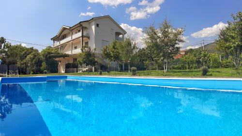 una grande piscina blu di fronte a una casa di Villa Mimoza Blagaj a Blagaj