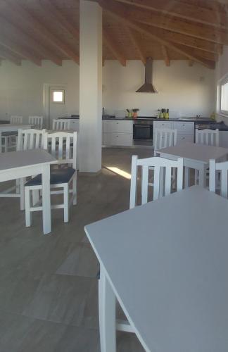 a white kitchen with white tables and white chairs at Monte Bagão - Turismo Rural in Vila do Bispo