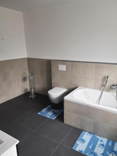 a bathroom with a tub and a toilet and a sink at Gäste Haus Am See in Düren - Eifel