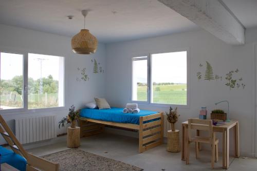 a bedroom with a bed with blue sheets and windows at Entheos in Lerín