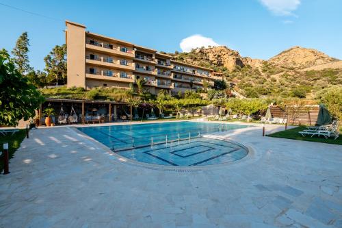 a hotel with a swimming pool in front of a mountain at The Maxine Hotel Adults Only in Agia Galini