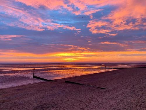 a sunset on a beach with the sun setting at Kingsway Hotel. in Cleethorpes