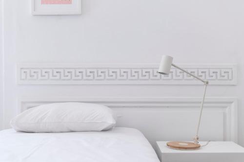 a white bed with a white pillow and a lamp at SLO Hostel Lyon les Pentes in Lyon