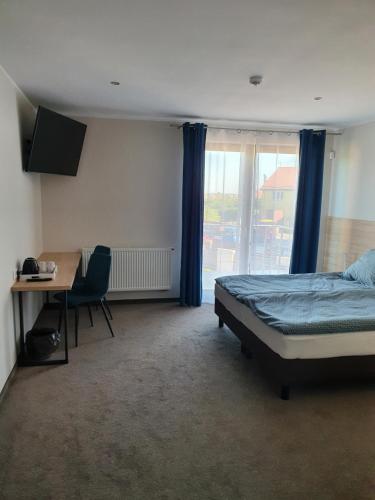 a bedroom with a bed and a desk and a window at Willa Maciejka in Gdańsk