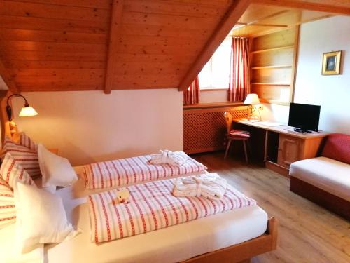ein Hotelzimmer mit zwei Betten und einem Schreibtisch in der Unterkunft Hotel Holzer in Sexten