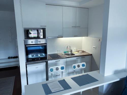 a white kitchen with a sink and a microwave at Apartment Azzurro lux in Novi Beograd